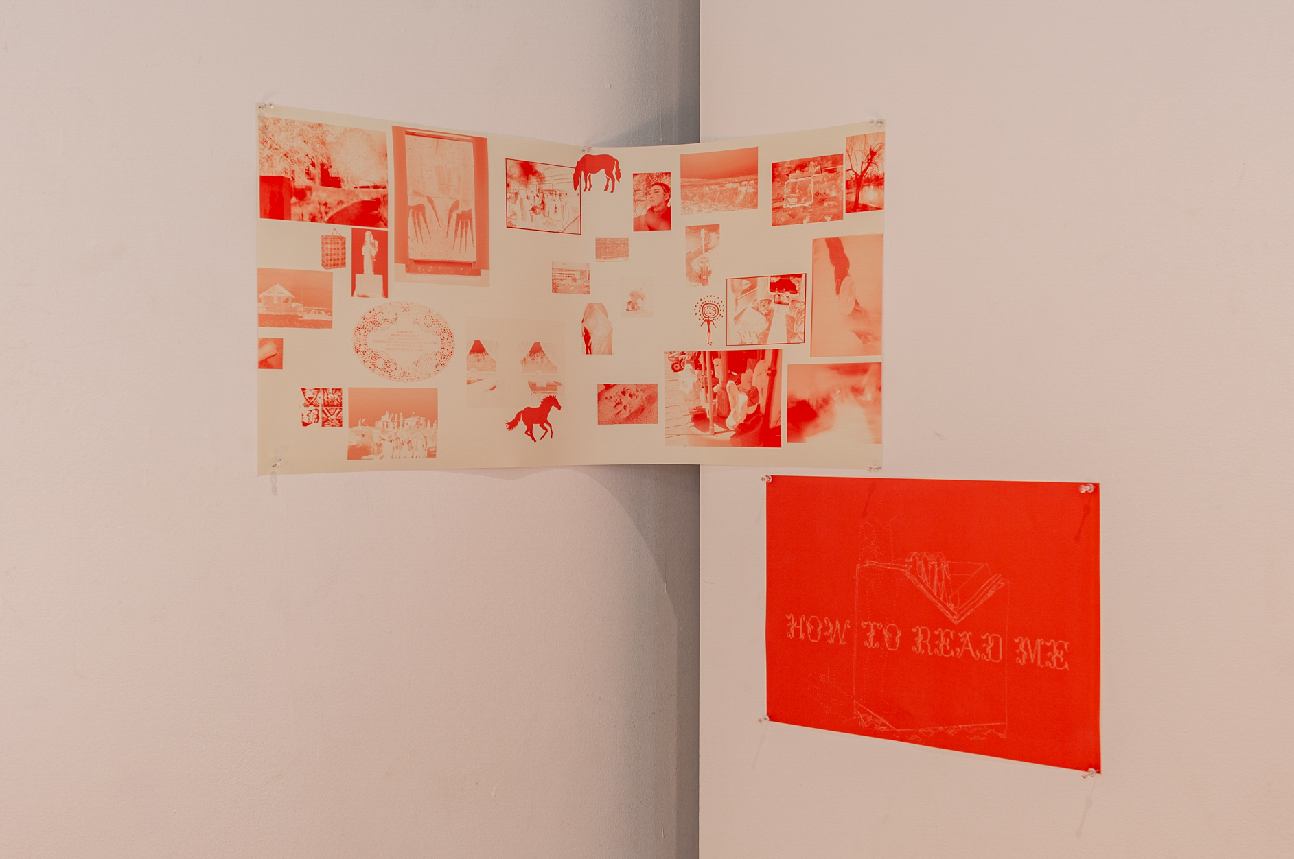 A diagram of photos and illustrations above a red paper with text saying How to Read me, displayed in the corner of a plain white wall.